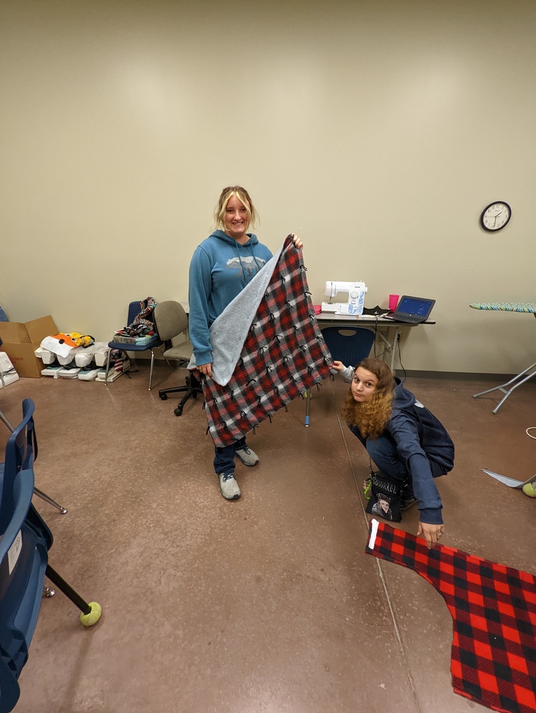 Brandi and Laci displaying a quilt Brandi made in sewing class.